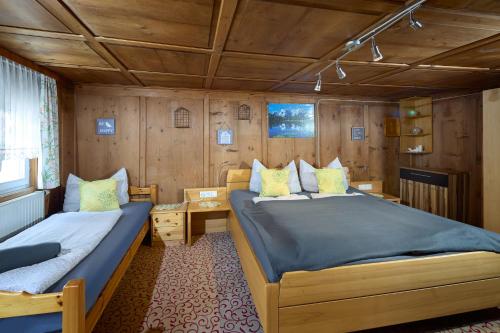 two beds in a room with wooden walls at Landhaus-Willi in Gaschurn