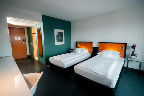 two beds in a hotel room with green walls at Dorint Kongresshotel Düsseldorf/Neuss in Neuss