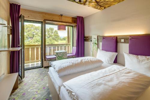 two beds in a room with purple walls and windows at Explorer Hotel Kitzbühel in Sankt Johann in Tirol