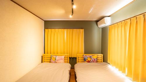 two beds in a room with yellow curtains at mintstay kochi in Kochi
