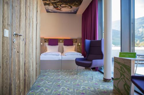 a small bedroom with a bed and a chair at Explorer Hotel Zillertal in Kaltenbach