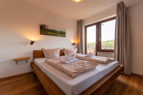 a bedroom with a large bed with a large window at Wolke 7 – PEAK Andreasberg in Sankt Andreasberg
