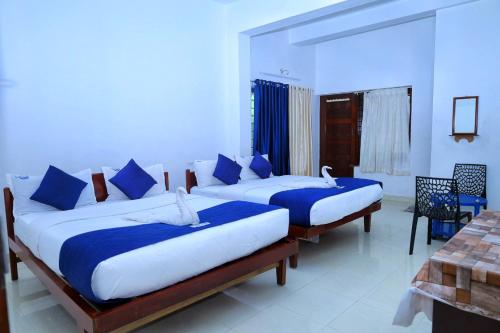 ein Schlafzimmer mit zwei Betten und blauen Kissen in der Unterkunft AC MIST in Munnar