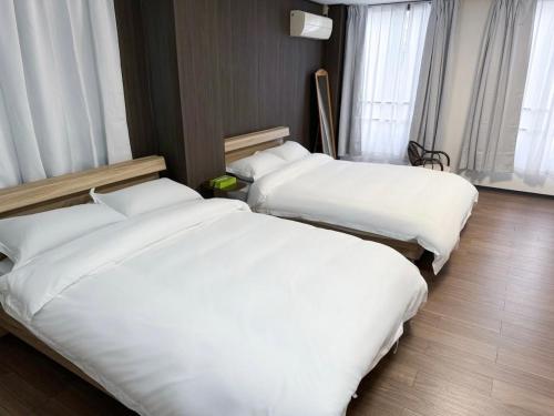 two beds in a hotel room with white sheets at 亀井町Stay202 in Takamatsu
