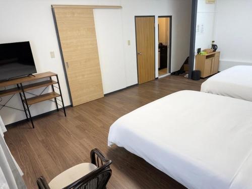 a hotel room with two beds and a flat screen tv at 亀井町Stay202 in Takamatsu