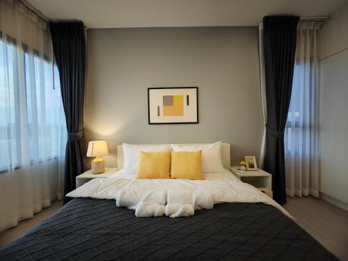 a bedroom with a large bed with yellow pillows at Cozy Breeze Onnut 21 in Amphoe Phra Khanong