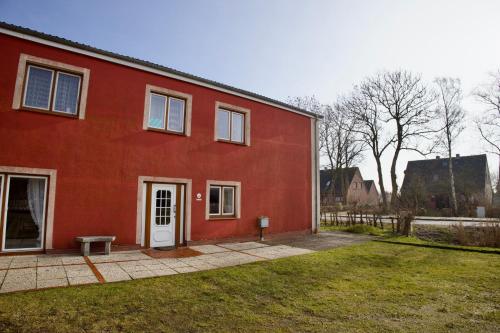 a red house with a white door and a bench at Seetuun-Hoff - Studio in Nordstrand