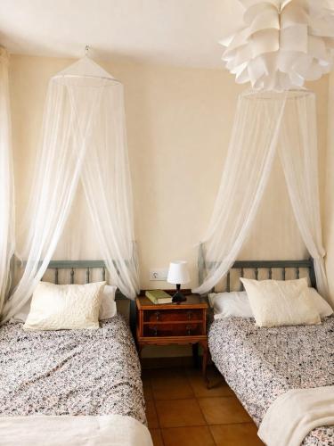 two beds in a bedroom with white curtains at Apartamento Rural la Fontanina TRCC0087 Complejo la Fontanina in Mata de Alcántara