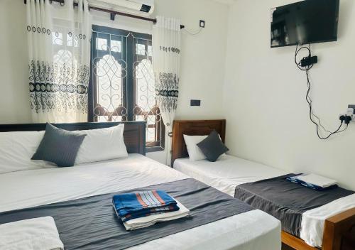 a room with two beds and a tv at Dilithy Paradise in Trincomalee