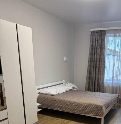 a white bedroom with a bed and a window at Надія in Khlibodarske