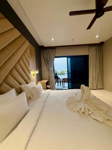 a bedroom with a large white bed with a ceiling fan at Riviera Hotel and Resort in Choli