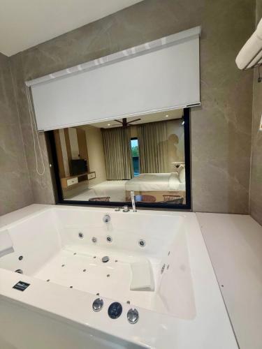 a bathroom with a bath tub with a large mirror at Riviera Hotel and Resort in Choli