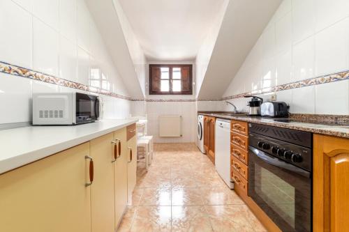 a kitchen with white cabinets and a microwave at Apartamento Bautista Centro in Cangas de Onís
