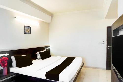 a bedroom with a large white bed with black pillows at Super Collection O Maninagar Formerly Park Land in Ahmedabad
