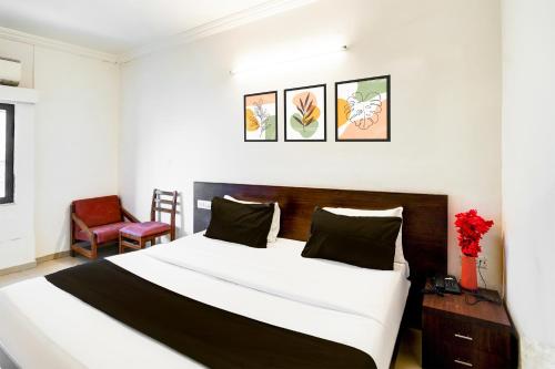 a bedroom with a large bed and a red chair at Super Collection O Maninagar Formerly Park Land in Ahmedabad