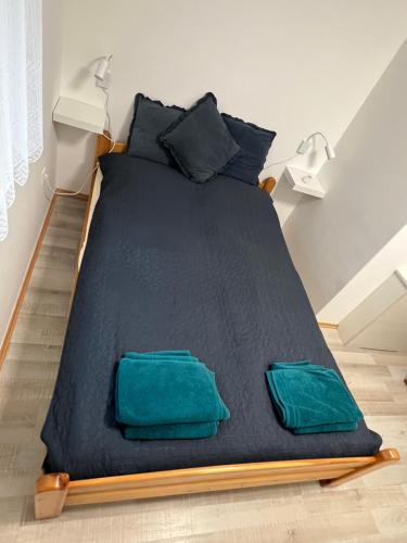a bed with black sheets and green pillows at Star Street Home in Mosonmagyaróvár