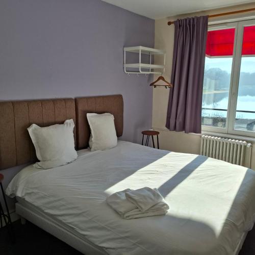 a bedroom with a bed with white sheets and a window at Hotel - Bistro - Bar Le Bellerive in Peyrat-le-Château