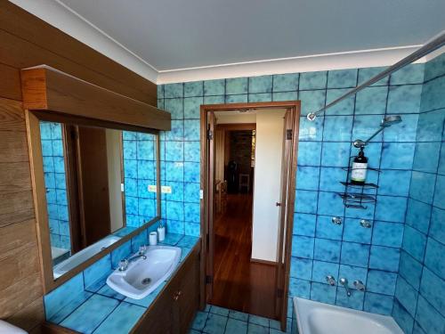 a blue tiled bathroom with a sink and a mirror at Crescent Clearwater - Revival in Crescent Head