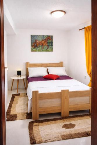 a bedroom with a wooden bed with a red pillow at Dabanović House in Virpazar