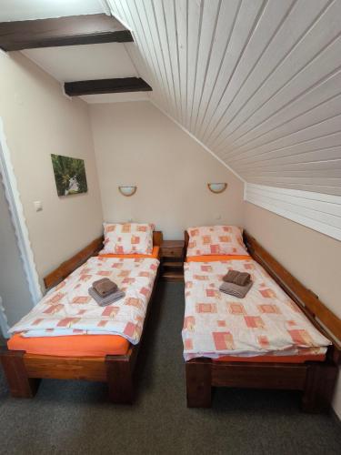 two beds in a room with a ceiling at Hotel Koloniál Skalité in Skalité