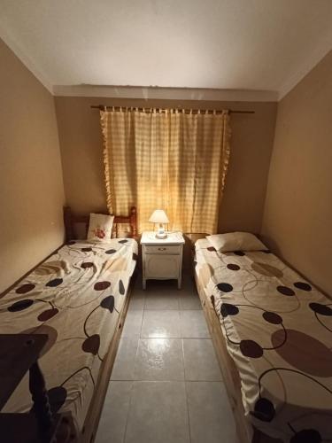 a bedroom with two beds and a table and a window at Electra hospedaje familiar in Chicoana