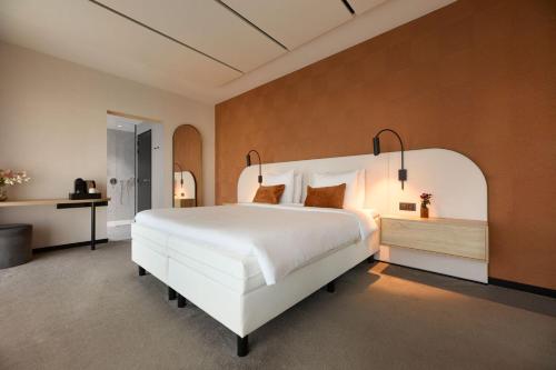 Van der Valk Hotel Gent في خنت: غرفة نوم بها سرير أبيض كبير ومكتب