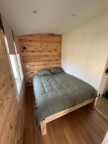 a bed in a small room with a wooden wall at La Roulotte des Gaillots in Moiremont