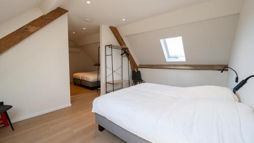 a bedroom with a white bed and a staircase at Vakantiehuis Bartholomé in Nieuwmunster