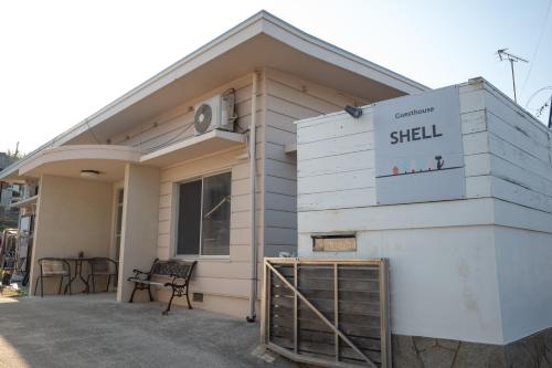 a small white building with a sign on it at Guesthouse SHELL in Naoshima