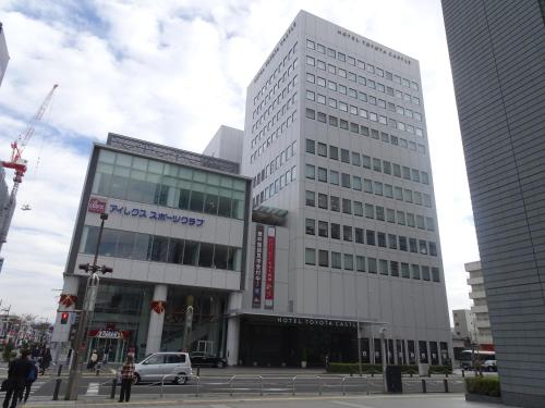 a tall white building in a city at Hotel Toyota Castle in Toyota