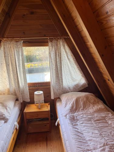 two beds in a attic bedroom with a window at Ferienhaus Finnhütte in Zinnowitz