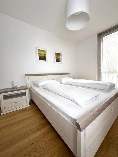 a white bedroom with a large white bed and a window at Seelavie in Podersdorf am See