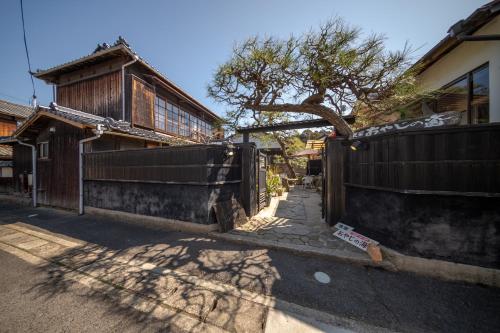 a fence in front of a house with a tree at Oyajino Umi in Naoshima