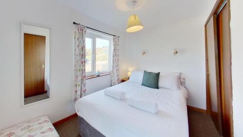 a bedroom with a white bed and a window at C35 Le Grace, Riviere Towans in Hayle