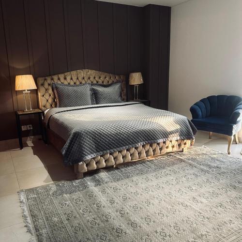 a bedroom with a large bed and a blue chair at One Constitution Avenue by Goldfinch, Luxury apartments near Diplomatic Enclave and Serena in Islamabad