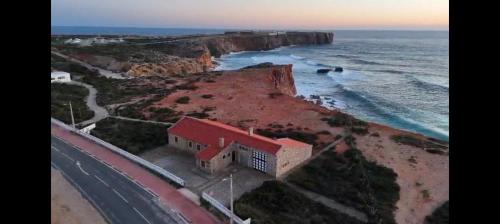 a building on a cliff next to the ocean at Casa dos Rebolinhos in Sagres