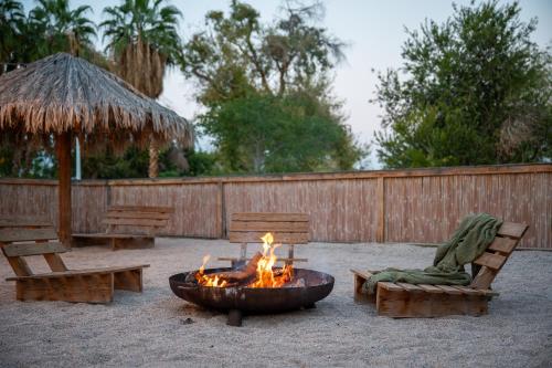 a fire pit in a yard with chairs and a umbrella at כפר נופש קלי"ה ים המלח in Kalia