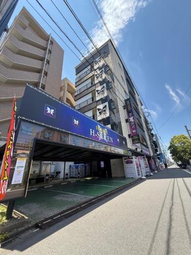 a building with a blue sign on the side of a street at H-Seven Nishikawaguchi (Adult Only) in Kawaguchi