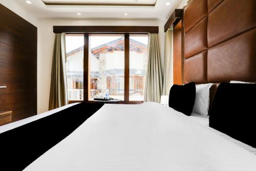 a bedroom with a large bed and a large window at Collection O Mall Road Nainital Formerly Urban Bliss in Nainital