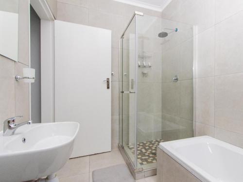 a white bathroom with a shower and a sink at Lady Daisy Boutique Guesthouse in Rustenburg