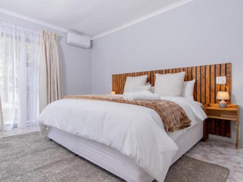 a bedroom with a large bed with a wooden headboard at Lady Daisy Boutique Guesthouse in Rustenburg
