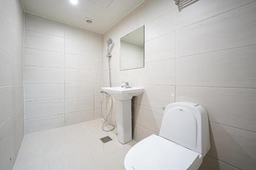 a white bathroom with a toilet and a sink at Midpoint Guesthouse in Busan