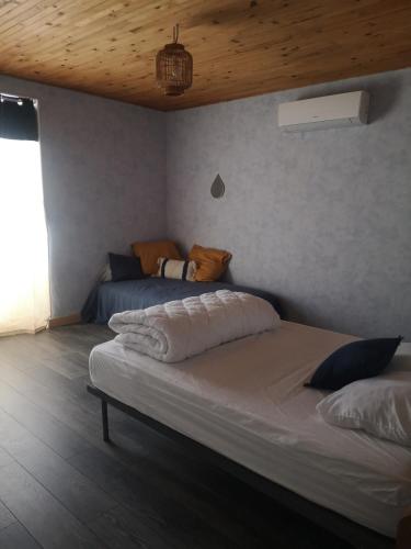 a bedroom with two beds and a wooden ceiling at Maison proche centre Les Vans in Les Vans