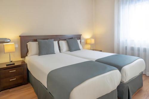 a large bed in a hotel room with two lamps at Pierre & Vacances La Merceria in El Tarter