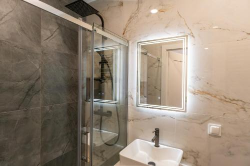 a bathroom with a shower and a sink and a mirror at Apartament Daisy Pszczyna Centrum in Pszczyna
