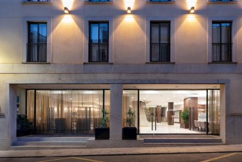 a facade of a building with a large glass storefront at Dorma Agora Cáceres in Cáceres