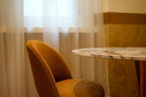 een tafel en een stoel naast een tafel en een gordijn bij The Talent Hotel in Rome