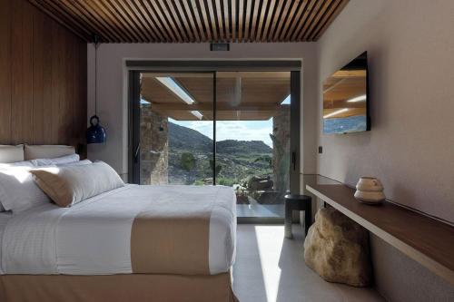a bedroom with a large bed and a large window at Crimson View Villa by Hide Out in Ios Chora