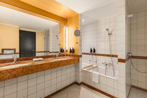 a bathroom with two sinks and a shower and a tub at Hotel Remarque in Osnabrück