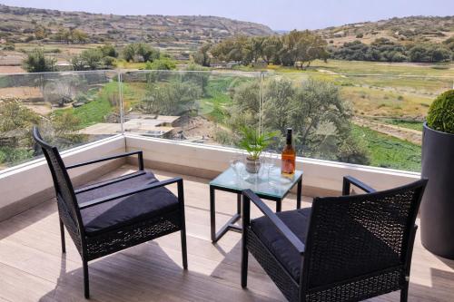 a balcony with a glass table and two chairs and a bottle of wine at Valley View in Qrendi